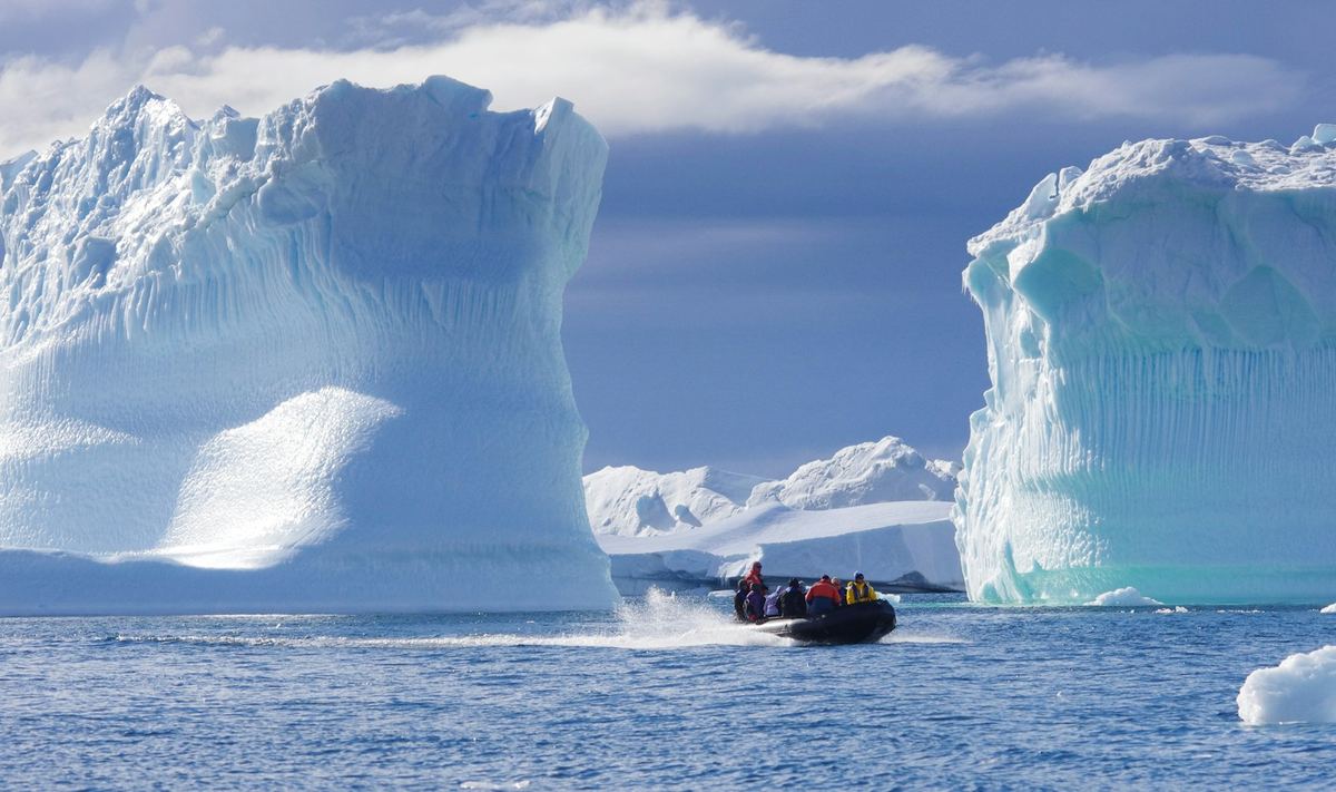 Expedition guests in a small boat among icebergs